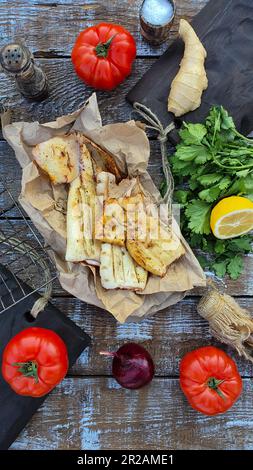 Die Hand einer Frau gießt Zitronensaft auf frisch gekochten Tintenfisch. Gegrillter Tintenfisch. Mediterrane Küche. Asiatische Küche. Stockfoto