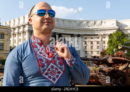 Kiew, Ukraine. 18. Mai 2023. Ein Mann, der ein traditionell gesticktes ukrainisches Hemd trägt, posiert am Mykhailivska-Platz, um am 18. Mai 2023 bei einer Ausstellung der russischen verbrannten Panzer in Zentral-Kiew, Ukraine, fotografiert zu werden. Der Weltvyshyvanka-Tag ist ein neuer ukrainischer Feiertag, der sowohl in der Ukraine als auch im Ausland gefeiert wird, um die Identität der Ukraine zu betonen, die mit der Folklorekultur verbunden ist. (Foto: Dominika Zarzycka/Sipa USA) Guthaben: SIPA USA/Alamy Live News Stockfoto