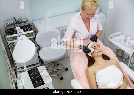 Kosmetikservice, Kosmetiktherapie, Hautreinigung, Gesichtstherapie, Schönheitsbehandlung, Gesichtsverjüngungsbehandlung, Gesichtsmassage beim Kosmetiker. Reinigung mit Wattepads Stockfoto