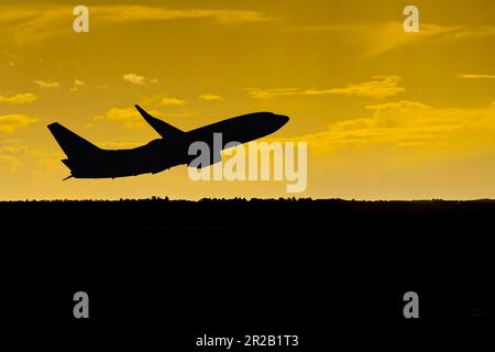 Silhouette eines Passagierflugzeugs, das bei Sonnenuntergang einen Flughafen verlässt. Keine Personen. Speicherplatz kopieren. Stockfoto