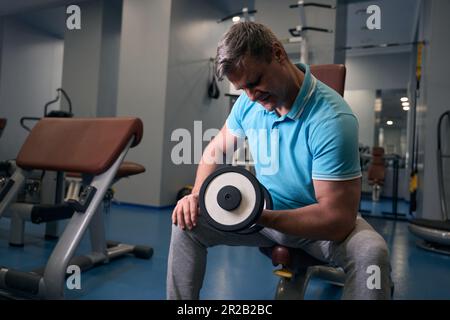 Ein hochkonzentrierter Bodybuilder, der Krafttraining im Fitnessstudio macht Stockfoto