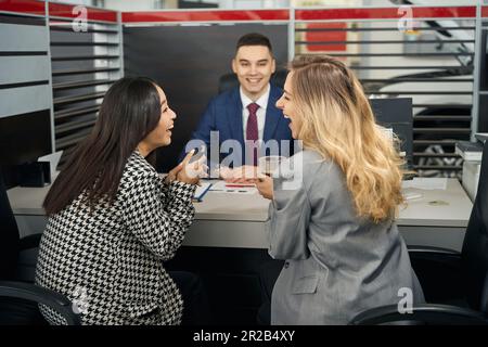 Zwei glückliche junge Frauen und ein Mann im Büro Stockfoto