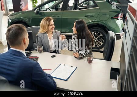 Der Autohändler kauft ein Auto für ein glückliches lgbt-Paar Stockfoto
