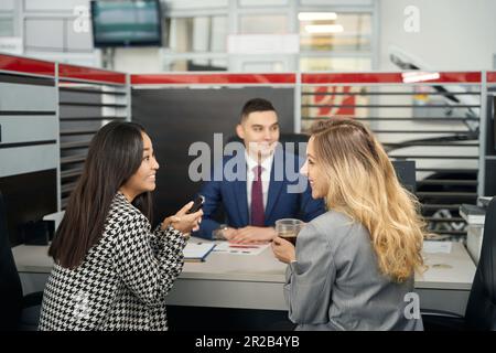 Fröhliches LGBT-Paar und ein Mann im Autohaus Stockfoto