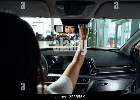 Junge Asiatin sitzt auf dem Fahrersitz Stockfoto