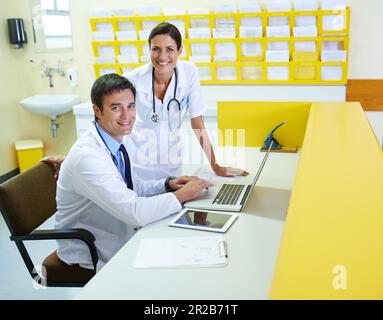 Ich schaue online nach den neuesten Forschungsergebnissen. Porträt eines gutaussehenden jungen Arztes und seiner Pflegehelferin mit einem Laptop. Stockfoto