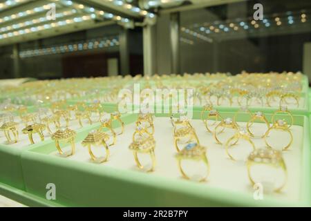Goldene Diamanten-Verlobungsringe werden im Schaufenster des Einzelhandelsgeschäfts gezeigt. Stockfoto