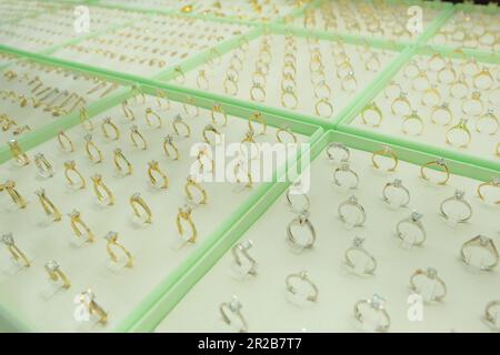 Goldene Diamanten-Verlobungsringe werden im Schaufenster des Einzelhandelsgeschäfts gezeigt. Stockfoto