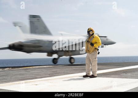 Chief Warrant Officer 3 William Sum, aus Panorama City, Kalifornien, dem erstklassigen Flugzeugträger USS Gerald R. Fords (CVN 78) Air Department zugeteilt, beobachtet eine F/A-18E, die den „Ragin“ Bulls von Strike Fighter Squadron (VFA) 37 auf dem Flugdeck zugeordnet ist, am 15. Mai 2023. VFA-37 wird an Bord von CVN 78 als Teil von Carrier Air Wing (CVW) 8 eingesetzt. Gerald R. Ford ist die USA Der neueste und fortschrittlichste Flugzeugträger der Navy, der einen Generationssprung in den USA darstellt Die Fähigkeit der Navy, Energie auf globaler Ebene zu projizieren. Die Gerald R. Ford Carrier Strike Group ist in einem geplanten Einsatz Stockfoto