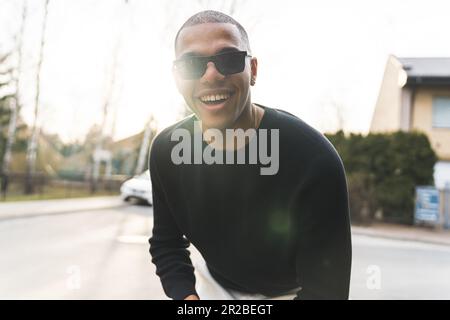 Fröhlicher und aufgeregter afroamerikanischer Glatzkopf mit Sonnenbrille, der sich im Freien, mittellange Nahaufnahme, Vergnügen kann. Hochwertige 4K-Aufnahmen Stockfoto