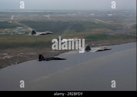 USA Air Force F-22 Raptors, die der 43D. Kampfgeschwader zugeteilt wurden, und ein T-38A Talon, die der 2D. Kampfgeschwader zugeteilt wurden, fliegen eine unterschiedliche Formation über dem Florida Panhandle, 10. April 2023. Die Formation war eine Hommage an die frühere Mission des 325. Fighter Wing, F-22 Raptor-Piloten fast 20 Jahre lang auszubilden. Der Flügel geht auf eine Kampfmission über, mit F-35A Lightning II Kampfflugzeuge, die in den nächsten Jahren ankommen. (USA Air Force Foto von Tech. Sgt. Betty R. Chevalier) Stockfoto