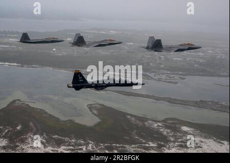 USA Air Force F-22 Raptors, die der 43D. Kampfgeschwader zugeteilt wurden, und ein T-38A Talon, die der 2D. Kampfgeschwader zugeteilt wurden, fliegen eine unterschiedliche Formation über dem Florida Panhandle, 10. April 2023. Die Formation war eine Hommage an die frühere Mission des 325. Fighter Wing, F-22 Raptor-Piloten fast 20 Jahre lang auszubilden. Der Flügel geht auf eine Kampfmission über, mit F-35A Lightning II Kampfflugzeuge, die in den nächsten Jahren ankommen. (USA Air Force Foto von Tech. Sgt. Betty R. Chevalier) Stockfoto