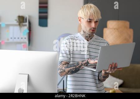Tätowierter Grafikdesigner, der mit einem Laptop im Büro arbeitet Stockfoto