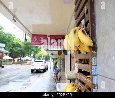 Reife Bananen hängen vor dem Yong Kang Fruit Garden Store, wo Obst und Gemüse in der Yongkang Street, im Da'an District, Taipei, Taiwan verkauft werden. Stockfoto