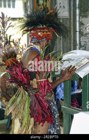 Papua-Neuguinea, östliche Highlands, Goroka, Eine junge papuanische Frau liest während der Heiligen Messe die Bibel. Ein junger Papua liest die Bibel. Stockfoto