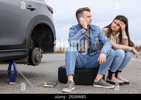 Ein junger Mann ruft beim Autoservice an. Reifenpanne Stockfoto