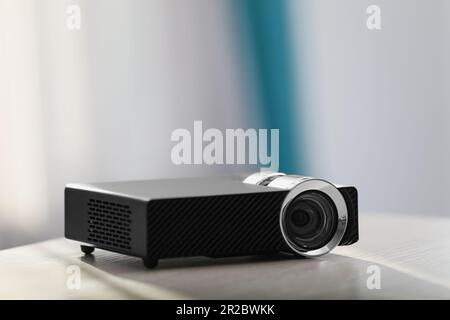 Moderner Videoprojektor auf weißem Tisch im Innenbereich Stockfoto