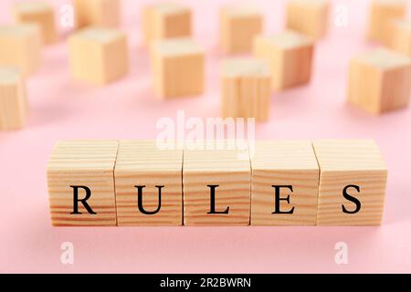 Wortregeln aus Holzwürfeln mit Buchstaben auf pinkfarbenem Hintergrund Stockfoto