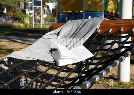 Komfortable NetzHängematte mit offenem Buch im Freien an sonnigen Tagen Stockfoto