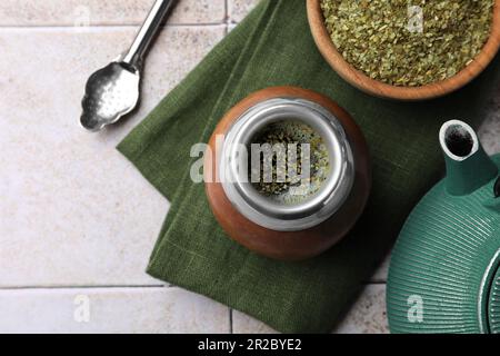 Calabash, Bombilla, Schüssel Teeblätter und Teekanne auf gefliestem Tisch, flach liegend Stockfoto