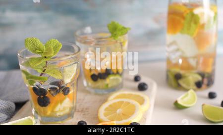 Sommerliche gesunde Cocktails aus Zitruswasser, Limonaden oder Mojitos, mit Limone Zitronenorange Blaubeeren und Minze, Diät Entgiftungsgetränke, in Gläsern Stockfoto