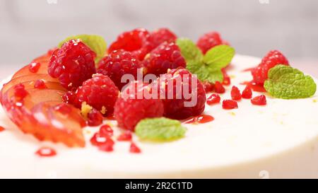 Käsekuchen mit frischen Himbeeren, Pflaumen und Minzblättern. Stockfoto