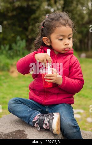 Lifestyle in einem Park, leckeres Jelly latin Girl mit gesammelten Haaren, lässige Kleidung, Utensilien zum Essen, geniessen süße Desserts Stockfoto