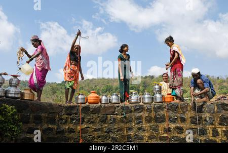 Mumbai, Indien. 16. Mai 2023. Dorfbewohner, die an der Grenzmauer stehen, ziehen Wasser aus dem Brunnen im Dorf Telamwadi in der Nähe von Vihigaon, Shahapur taluka des Bezirks Thane in der Nähe von Mumbai. Die Dorfbewohner sind während der Sommermonate mit akuter Wasserknappheit konfrontiert, da sie durch einen Wassertransporter, der nur einmal am Tag Wasser in den Brunnen entlädt, Wasser erhalten, was für sie und ihre Rinder für den täglichen Gebrauch nicht ausreicht. (Foto: Ashish Vaishnav/SOPA Images/Sipa USA) Guthaben: SIPA USA/Alamy Live News Stockfoto