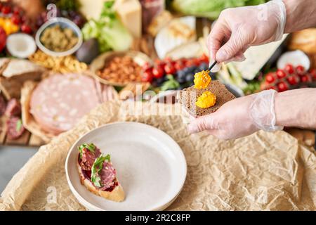 Der Kellner macht Bruschetta oder Tapas. Tisch voller mediterraner Vorspeisen, Tapas oder Antipasto. Auswahl an italienischen Speisen. Köstlicher Snack auf der Party Stockfoto