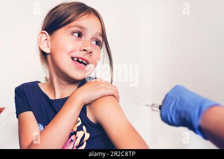 Ein kleines Mädchen schreit aus Angst, in die Schulter geschossen zu werden. Impfung gegen gefährliche Viruserkrankungen. Prävention und Schutz vor Viren. Inj Stockfoto