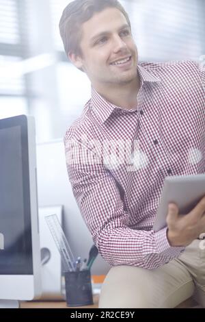 Angenehm überrascht von den neuesten Zahlen. Ein attraktiver junger Geschäftsmann, der ein digitales Tablet in seinem Büro benutzt. Stockfoto