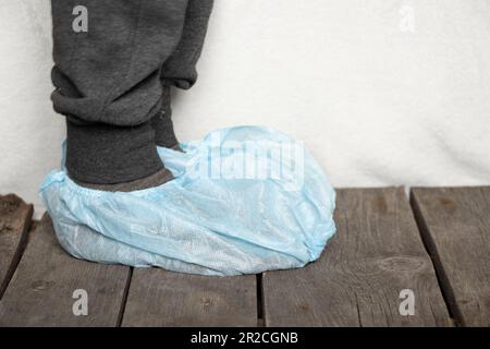 Weibliche Beine in blauen medizinischen Plastikschuhüberzügen im Krankenhaus Stockfoto