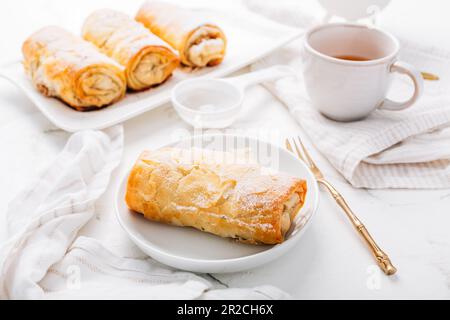 Hausgemachter Apfelstrudel mit Zimt, Apfelkuchen mit einer Tasse Obsttee Stockfoto