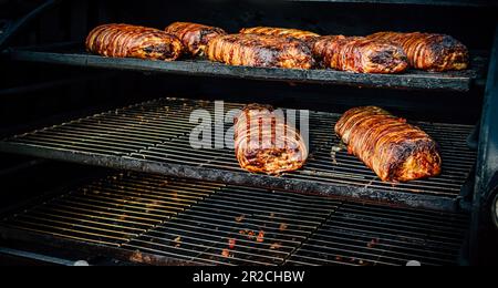 Großer Barbecue-Rauchergrill im Park. Fleisch und Speck, zubereitet im Barbecue-Raucher. Stockfoto