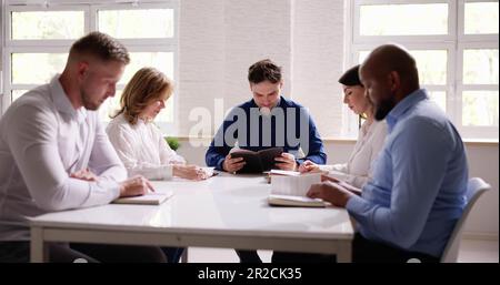 Gruppe von Jungen multiethnischen Menschen Lesen der Bibel über Holz- Schreibtisch Stockfoto