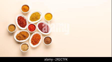 Verschiedene getrocknete Gewürze in kleinen Schüsseln auf beigefarbenem Tisch. Flach liegend mit Kopierbereich Stockfoto