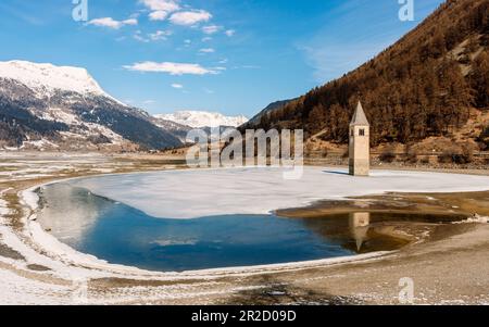 Der berühmte Glockenturm aus dem 14. Jahrhundert in Reschensee, der Reschen-See und das alte untergetauchte Dorf Graun. Reschen Pass, Vinschgau Valley, Südtirol, Italien. Stockfoto