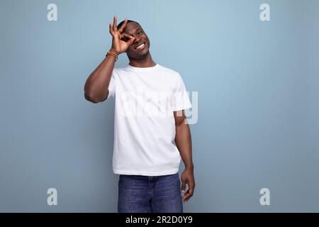 Selbstbewusster, gutaussehender, dunkelhäutiger junger amerikaner in einem weißen T-Shirt vor dem Hintergrund mit Kopierbereich Stockfoto