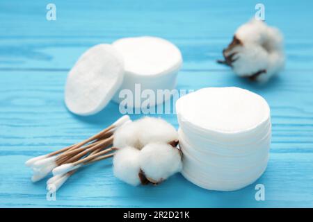 Wattestäbchen und -Stäbchen mit Blüten auf blauem Hintergrund. Draufsicht Stockfoto