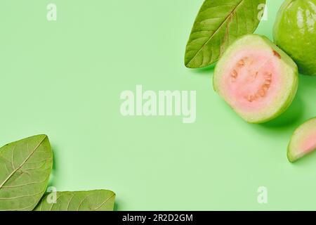 Draufsicht, flach liegend Pink Guava Slice Fruit mit frischen grünen Blättern isoliert auf grünem Hintergrund. Für copy space.copy Text.for Advertising Design.Fruits Stockfoto