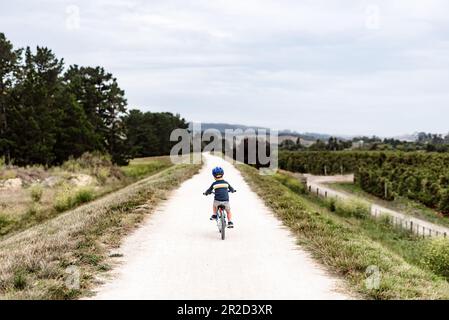 Ein kleiner Junge, der mit dem Fahrrad auf einem abgelegenen Pfad in Neuseeland fährt Stockfoto