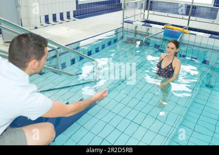 Schwangere Frau im Schwimmbad, die mit dem Trainer spricht Stockfoto