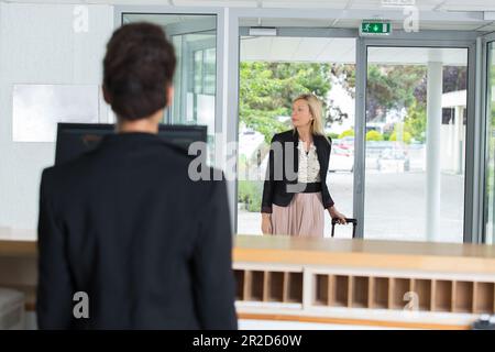 Freundliche junge Frau an der Rezeption, die den Gast begrüßt Stockfoto