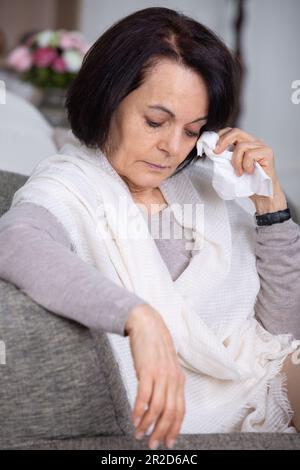 Eine verärgerte Frau weint auf dem Sofa Stockfoto