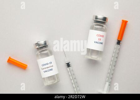 Coronavirus COVID-19-Impfstofffläschchen und Spritze auf grauem Hintergrund mit Kopierraum. Draufsicht Stockfoto