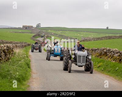 Ein Traktor fährt auf einer Straße über Settle, Yorkshire Dales, Großbritannien. Stockfoto