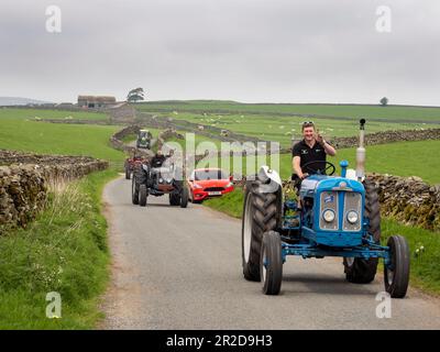 Ein Traktor fährt auf einer Straße über Settle, Yorkshire Dales, Großbritannien. Stockfoto