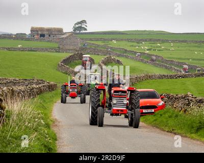 Ein Traktor fährt auf einer Straße über Settle, Yorkshire Dales, Großbritannien. Stockfoto