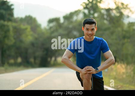 Motivierter Sportler, der sich vor dem Workout im Park dehnt. Fitness, Sport und gesundes Lifestyle-Konzept Stockfoto