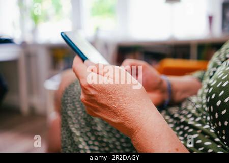 Frau, die zu Hause ein Smartphone verwendet. Tippen auf dem Smartphone. Technologie und Geschäftskonzept. Konzentriere dich auf die Hand. Stockfoto